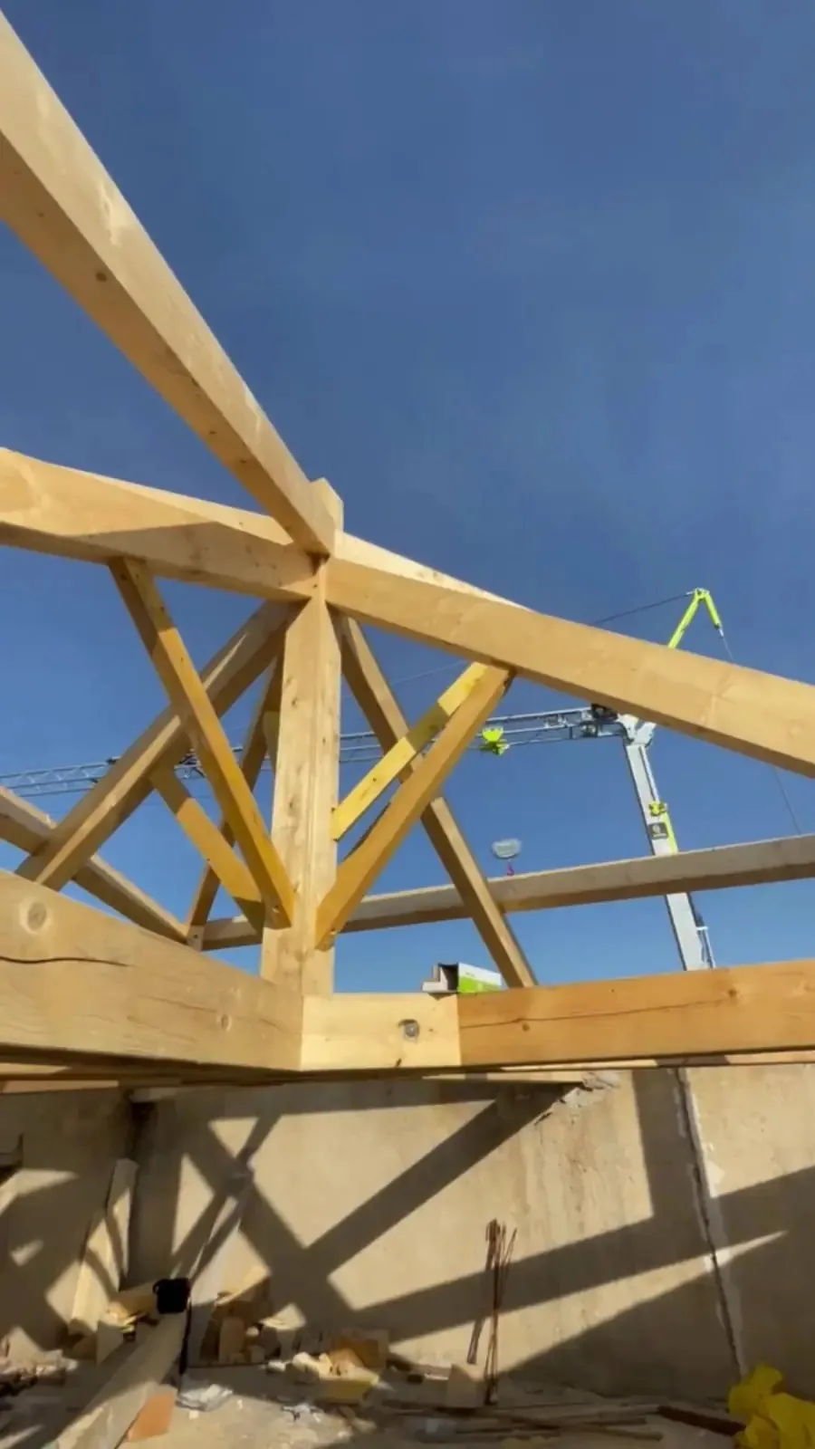 Charpente en bois en cours de montage, grue de chantier en arrière-plan