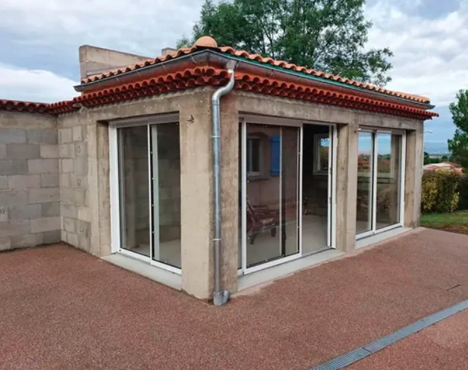 Extension de maison en blocs avec baies vitrées sur une terrasse